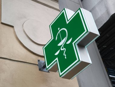 Prag, Çek Cumhuriyeti - 15 Nisan 2025: Asklepius çubuğu ve binanın ön cephesinde asılı adalet sembolü pullarıyla yeşil eczane kesişiyor
