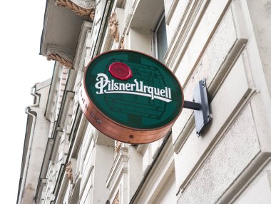 Prag, Çek Cumhuriyeti - 15 Nisan 2025: Prag, Czech cumhuriyetindeki bir binada asılı yeşil pilsner urquell bira amblemi işareti, bu ünlü bira fabrikasının ikonik markasını gösteriyor
