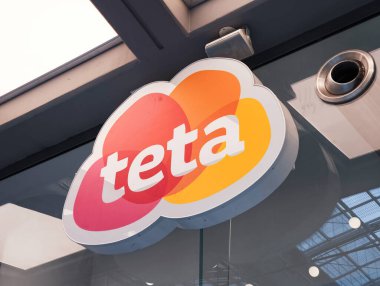 Prag, Çek Cumhuriyeti - 15 Nisan 2025: Bir mağazanın tavanından sarkan, kırmızı, turuncu ve sarı bölümlü bir buluta benzeyen teta süpermarket logosuna yakından bakın