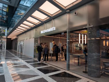 Prag, Çek Cumhuriyeti - 15 Nisan 2025: Çağdaş bir alışveriş merkezinde yer alan McDonalds restoranındaki self servis büfelerini kullanan insanlar