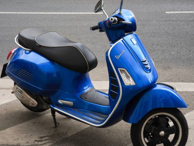 Prag, Çek Cumhuriyeti - 15 Nisan 2025: Şehrin kaldırımında parlayan mavi Vespa scooter 'ı klasik tasarımı ve canlı rengini gözler önüne seriyor
