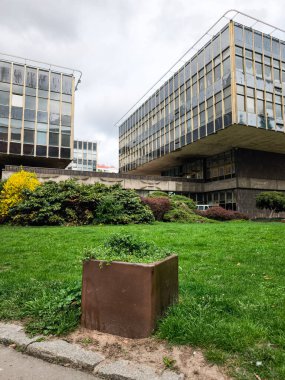 Prag, Çek Cumhuriyeti - 15 Nisan 2025: Prag 'daki planlama ve geliştirme enstitüsü önünde yeşil çimenlik ve çiçek bahçesi, sosyalist gaddar mimarinin bir örneği