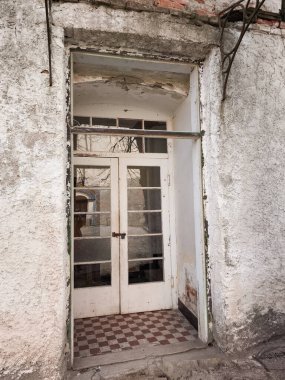 Brno, Çek Cumhuriyeti - 5 Nisan 2025: Kırılan alçı ve yıpranmış ahşap çerçeve, kareli zemin ile çürüyen bir giriş, Veveri Kalesi 'ndeki zamanın geçişini işaret ediyor