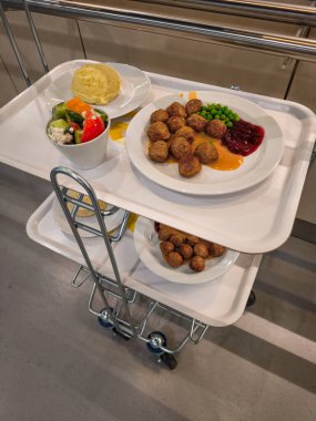 Prag, Çek Cumhuriyeti - 12 Nisan 2025: Patates püresi, salata, et suyu, yaban mersini sosu ve bezelye ile servis edilen lezzetli İsveç köfteleri