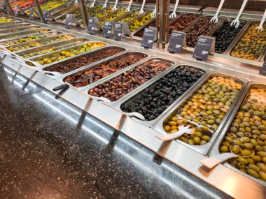 Prag, Çek Cumhuriyeti - 12 Nisan 2025: Çeşit çeşit zeytinli metal tepsiler, kurutulmuş domatesler ve Hypermarket globus 'ta self-servis için hazır diğer antipastiler