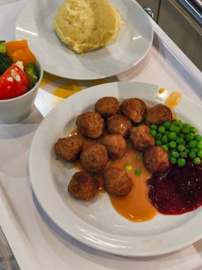 Prag, Çek Cumhuriyeti - 12 Nisan 2025: Soslu, ezilmiş patatesli, yaban mersini soslu, bezelyeli ve Prag, Czechia 'da yan salatalı klasik ikea yemeğinin tadını çıkarmak