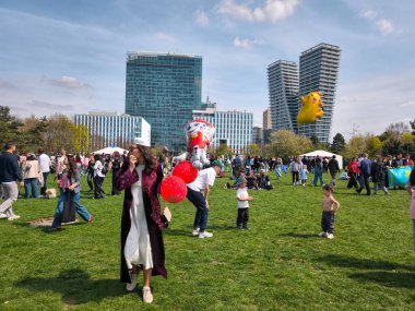 Prag, Çek Cumhuriyeti - 12 Nisan 2025: Elinde kırmızı balonlar tutan Kazak kadın aile ve şişme karakterlerle dolu Prag parkında kutlama yapıyor