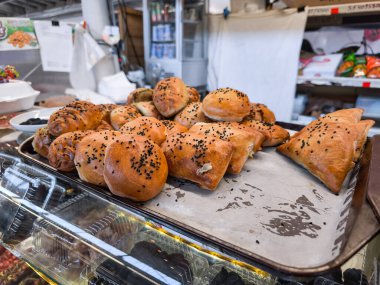 Geleneksel bir pazarda veya fırında, üzerinde siyah susam tohumları bulunan taze pişmiş Özbek hamur işleri. Prag Holesovice pazarında tipik Orta Asya sokak yemekleri, Çek Cumhuriyeti