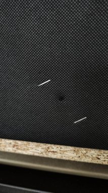 Parçacık tahtasına siyah kumaş bağlayan iki zımba, diy ve döşeme kavramlarını vurguluyor