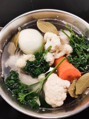 Taze karnabahar, havuç, soğan, maydanoz ve körfez yapraklarıyla kaynayan otlu sebze çorbası. Çorba yapmak için sebze pişiriyorlar.