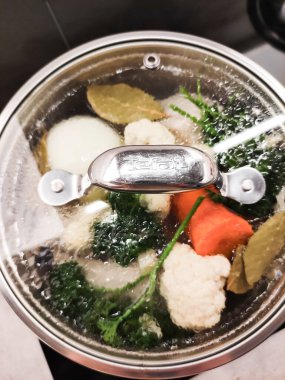 Prag, Çek Cumhuriyeti - 17 Ağustos 2024: Taze karnabahar, havuç, soğan, maydanoz ve körfez sebze çorbası yapmak için sebze pişiren akromatik sebze çorbası