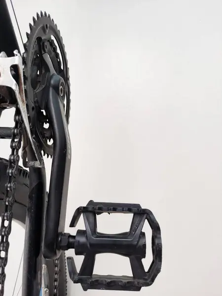 Bir krank-set 'e eklenmiş siyah bisiklet pedalının yakın görüntüsü, karmaşık tasarım ve işlevselliği gösteriyor, bisiklet bileşenlerinin işçiliğini ve mühendisliğini vurguluyor