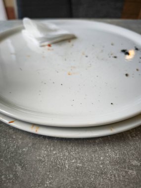 Boş tabaklar ve masada bir peçete bir yemek deneyiminin kalıntılarını ve bir yemeğin tadını ön plana çıkarıyor.