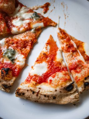 Üzeri erimiş dört peynirle kaplı pizza dilimleri ve beyaz bir tabakta leziz bir yemek sergileniyor. Kabuğu mükemmel pişmiş, tatmin edici bir yemek deneyimi yaşatıyor. Boşluğu kopyala
