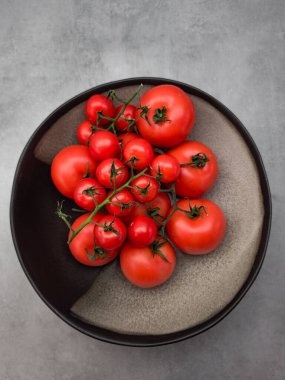 Canlı kırmızı domatesler ve kiraz domatesleri modern seramik bir plaka üzerinde renkli bir görüntü yaratarak, arka planda yeni üretilen duvar kağıdı kopyalama alanının güzelliğini gözler önüne seriyor.