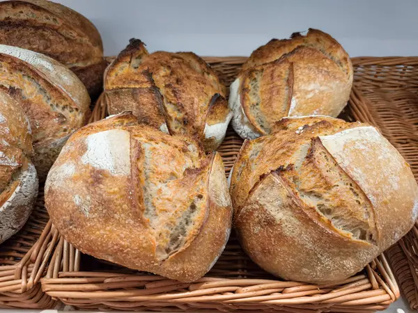 Yuvarlak ekşi ekşi somunlar hasır tepside soğuyor, altın kabuklarını sergiliyorlar ve zanaatkar pişirme tekniklerini sergiliyorlar.