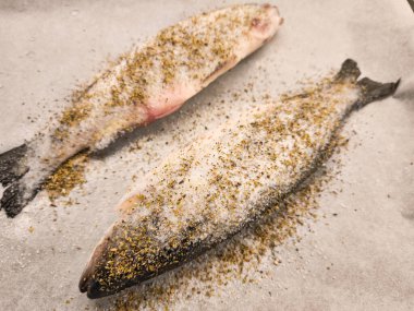 İki tam balık, tuzlu ve aromatik otlarla tatlandırılmış, fırında lezzetli bir yemek için sabırsızlıkla sıralarını bekliyorlar.