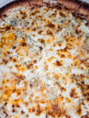 Lezzetli dört peynirli pizza Prag restoranında pişiyor, erimiş peynir karışımı sergiliyor.