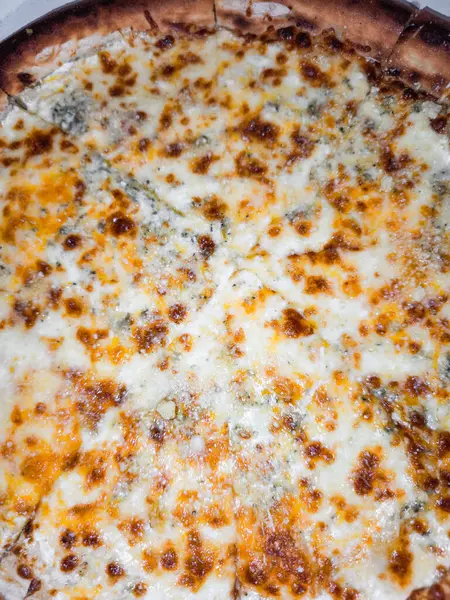 Lezzetli dört peynirli pizza Prag restoranında pişiyor, erimiş peynir karışımı sergiliyor.