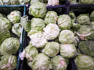 Pazar vitrininde sergilenen taze yeşil lahanalar sağlıklı beslenme seçeneklerinin önemini vurgulayarak canlı renklerini ve dokularını vurgular.