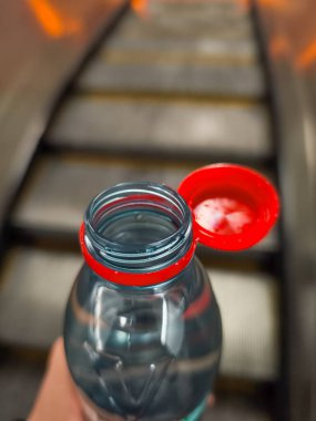 Prag, Çek Cumhuriyeti - 30 Nisan 2025: Yürüyen merdivenler arka planda yükselirken açık su şişesi Vittel Prag, Czechia 'daki kentsel yaşamın özünü yakalıyor