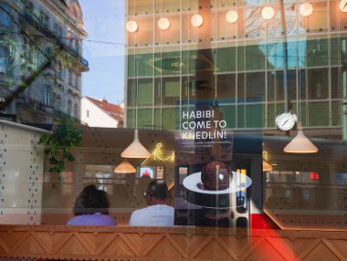 Prag, Çek Cumhuriyeti - 30 Nisan 2025: Modern bir diz kapağı restoranında, üzerinde Habibi yazılı geleneksel Çin mantısı reklamı olan iki müşteri Knedlin 'e geliyor.