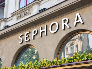 Prag, Çek Cumhuriyeti - 30 Nisan 2025: Prag 'da sarı çiçekli ve dekoratif mimari detaylara sahip bir binanın ön cephesinde büyük aydınlatılmış Sephora tabelası