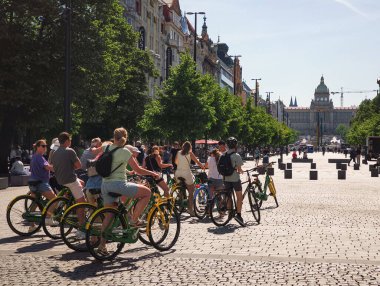 Prag, Çek Cumhuriyeti - 30 Nisan 2025: Güneşli bir günün tadını çıkaran turistler Wenceslas Meydanı, Prag 'da kiralık bisiklete biniyorlar.