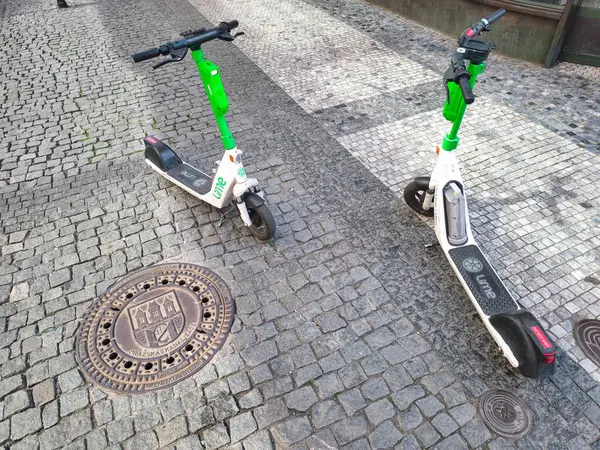 Prag, Çek Cumhuriyeti - 30 Nisan 2025: Prag, Czechia 'da bir kaldırım taşı caddesinde park etmiş iki elektrikli scooter tarihi bir ortamda modern bir ulaşım çözümü sunuyor