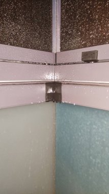 Duş kabini kapanıyor, cam yüzeyden süzülen su damlaları banyoda ferahlatıcı ve temiz bir atmosfer yaratıyor.