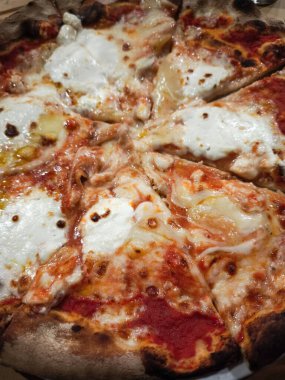 Kabaran peynirli ve domates soslu ahşap kaplı pizzaya yaklaş. Mükemmel kavrulmuş kabuk ve iştah açıcı malzemeler sergiliyorsun.