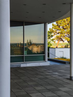 Prag, Çek Cumhuriyeti - 6 Mayıs 2025: Panoramik pencere, Letna Park 'taki modern bir binadan Prag şehir manzarasını yansıtıyor, mimari tasarım ve kentsel manzara sergileniyor