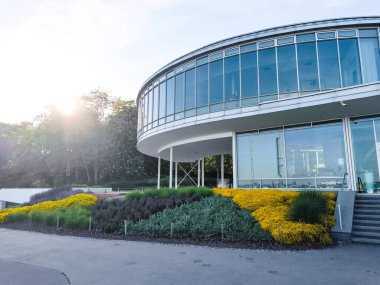 Prag, Çek Cumhuriyeti - 6 Mayıs 2025: Günışığı ağaçların arkasında parlıyor ve Letna Park, Prag, Czechia 'daki modern dairesel yapıyı aydınlatıyor
