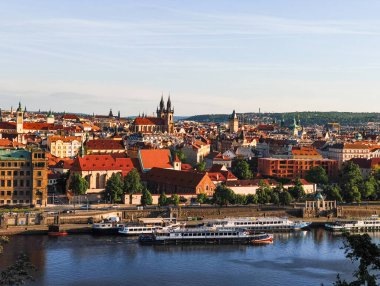 Prag, Çek Cumhuriyeti - 6 Mayıs 2025: Vltava nehri, turizm tekneleri, tarihi binalar ve Letna Park 'tan güneşli bir gökyüzü altında Prag kiliselerinin panoramik manzarası