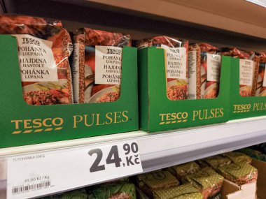 Prag, Çek Cumhuriyeti - 6 Mayıs 2025: Prag, Czech cumhuriyetindeki bir tesco süpermarketinde rafta sergilenen karabuğday Groats paketleri, bu temel gıdanın perakende sunumunu vurguluyor
