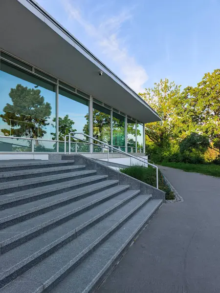 Prag, Çek Cumhuriyeti - 6 Mayıs 2025: Ağaçları yansıtan cam cepheli modern bina, Letna Parkı, Prag, Czechia 'da yer alıyor.