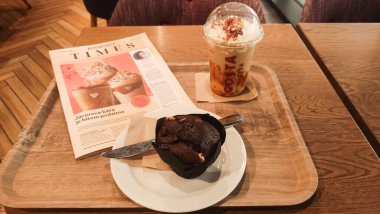 Prag, Çek Cumhuriyeti - 11 Eylül 2024: Prag 'da Costa Coffee' de dinlenmek, gazete okurken lezzetli bir kahve ve kekin tadını çıkarmak