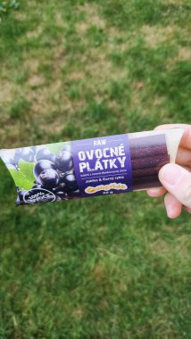 Prag, Çek Cumhuriyeti - 10 Eylül 2024: Prag fotokopi alanında elma ve siyah frenk üzümü aromalı bir ovnosnike meyve büfesi paketi tutan kişi