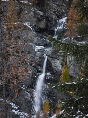 Şelaleler kayalık araziye dökülüyor, dağlık aosta içindeki altın sonbahar yapraklarıyla çerçevelenmiş, mevsimlik İtalyan manzarası Lillaz ortaya çıkıyor.
