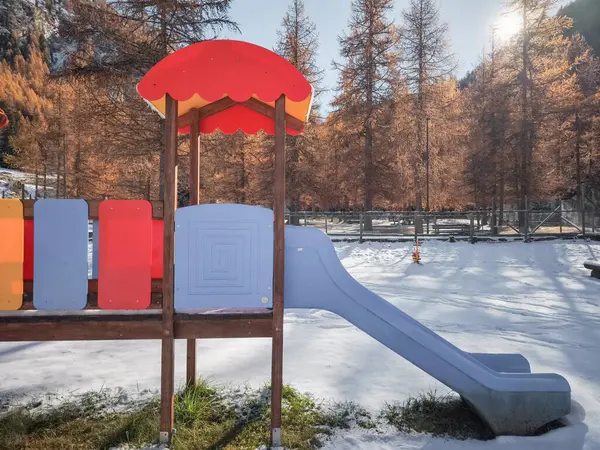 Renkli oyun alanı ekipmanları, İtalya 'nın Aosta kentindeki karlı zemin ve sonbahar ağaçlarıyla çelişiyor ve sakin bir Kasım manzarası yakalıyor.