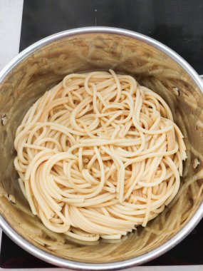 Taze haşlanmış bukatini makarnasını metal bir tencerede kurutmak, lezzetli bir İtalyan yemeği hazırlamak için bir sonraki adım için hazırlanmak, mutfak geleneği ve ev yapımı iyilik ile dolu.