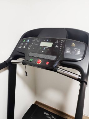 Prague, Czech Republic - September 08, 2022: Domyos T500C treadmill sleek control panel with digital display, buttons, and emergency stop, set in a modern home gym environment, fitness and health