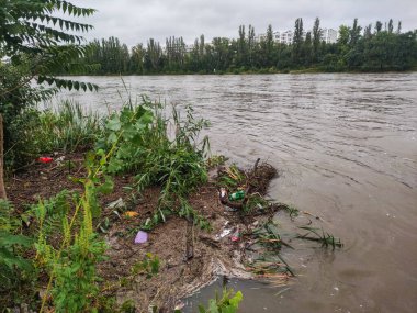 Prag, Czech Cumhuriyeti - 16 Eylül 2024: Vltava Nehri 'nin çamurlu suları, Prag' ın kıyılarını sonbahar yağmurlarından sonra sular altında bırakarak bulutlu bir gökyüzü altında enkaz taşır.