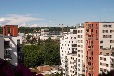 Prag, Çek Cumhuriyeti - 20 Mayıs 2024: Balkonların ve geniş pencerelerin bulunduğu modern konut binaları açık mavi gökyüzüne karşı yükseliyor, yemyeşil ağaçlı şehir manzarası