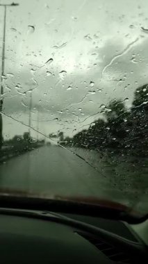 Yağmur damlalarının dikey yüksek kalitede görüntüsü cam pencereden şehrin siluetini bulanıklaştırıyor, bibione, İtalya 'da yağmurlu bir yaz gününde kasvetli şehir manzarası. Yüksek kaliteli FullHD görüntüler