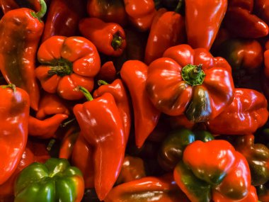 Canlı kırmızı ve yeşil biberler, yeni toplanmış, yerel bir çiftçi pazarında görsel olarak çekici bir görüntü oluşturarak, doğanın güzelliğini gözler önüne seriyor.