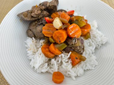 Kızarmış tavuk ciğeri ve havuç, biber ve soğan da dahil olmak üzere karışık sebzeler kabarık beyaz pirinç yatağının üzerinde servis edilir lezzetli ve besleyici bir yemek oluşturur.