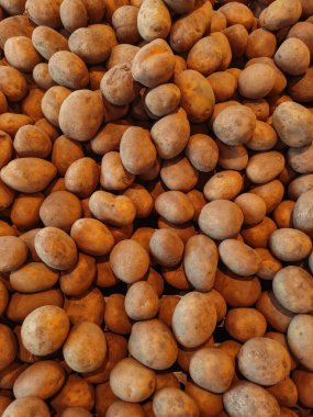 Birçok patates görsel olarak çekici bir arka plan yaratıyor, pazar ortamında bolluk ve tazelik öneriyor, tarım ve aşçılık temaları için mükemmel.