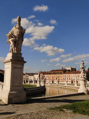 Padua, İtalya - 30 Haziran 2024: Prato della valle plazasını çevreleyen mermer heykeller, parlak gök kubbe altında süslü mimari su yollarının yer aldığı