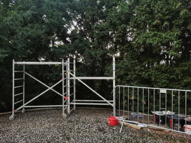 Prag, Çek Cumhuriyeti - 8 Temmuz 2024: İnşaat iskelesi, kova ve inşaat malzemeleri, Grebovka havlickovy sady parkındaki yeşil bir çitin yanına kurulmuştur.